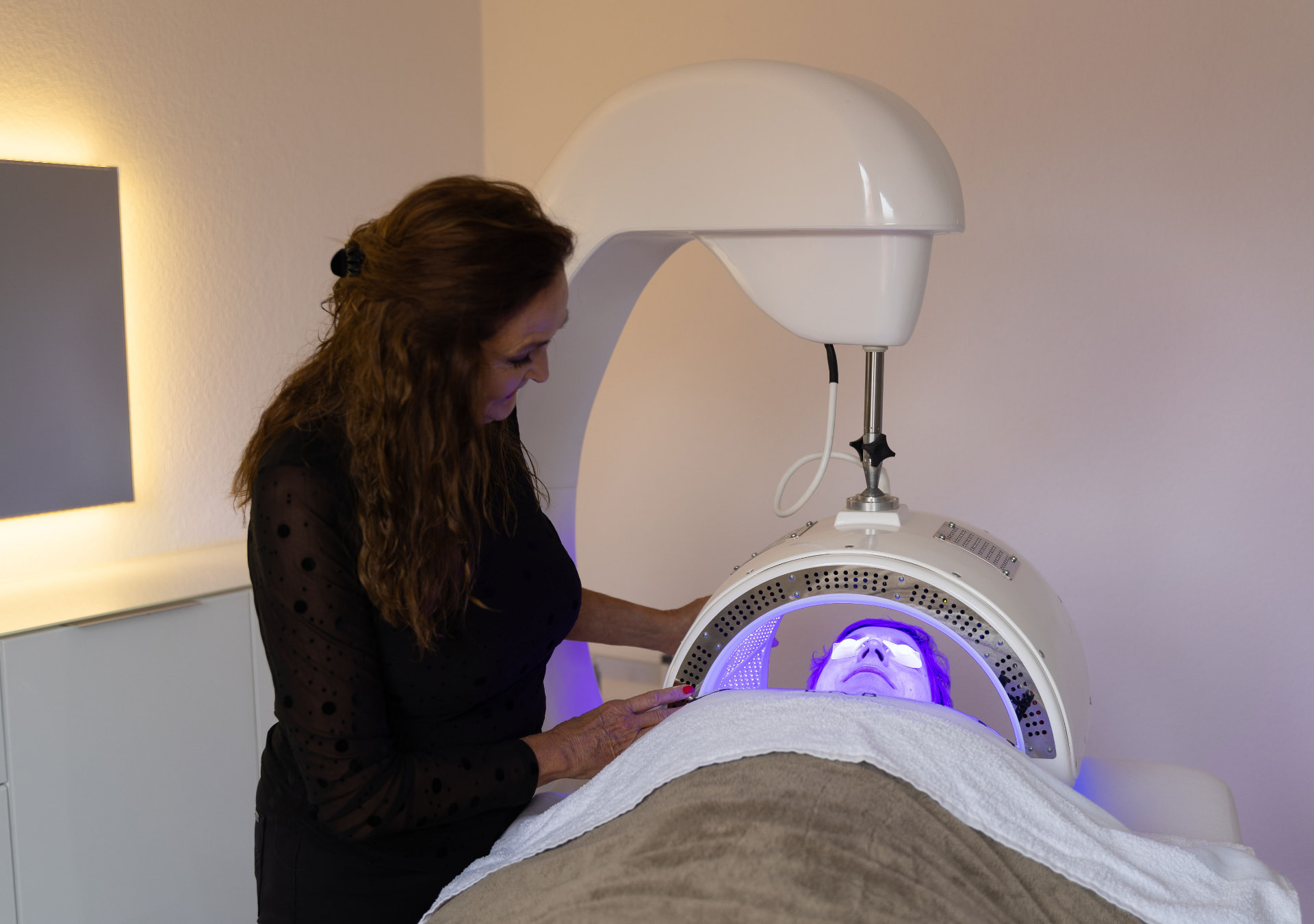 Specialiste van Cosmetix Salon begeleidt een Dermalux TRIWAVE LED-behandeling met blauw licht