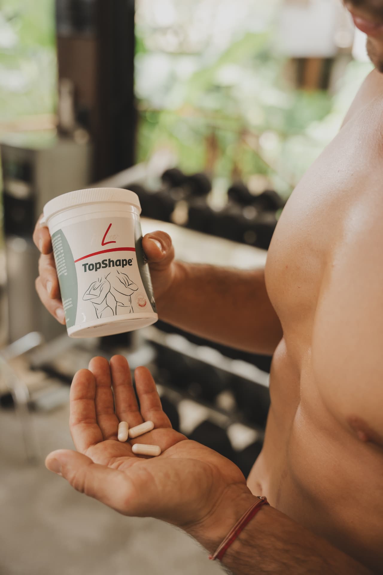 FitLine TopShape capsules in de hand na een training in de sportschool