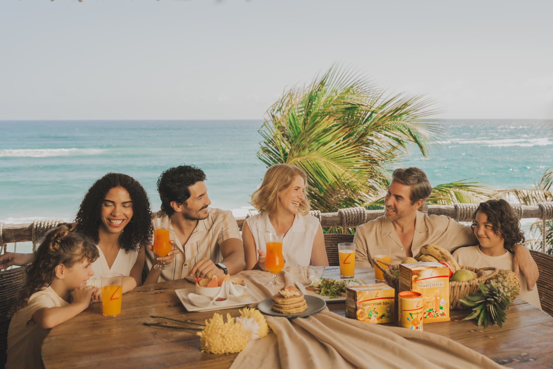 Gezin aan het ontbijt bij de zee met glazen FitLine PowerCocktail op tafel