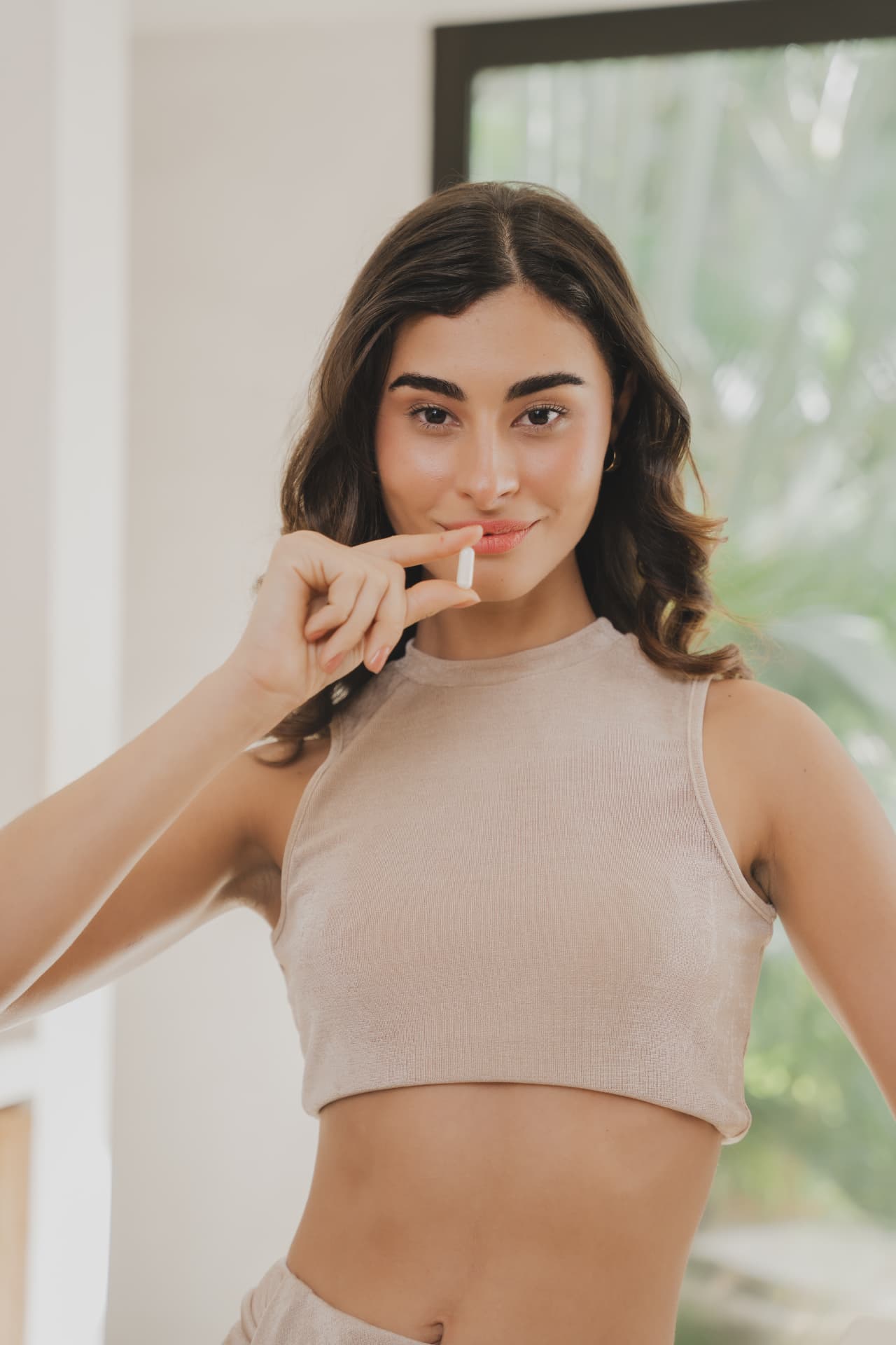Portret van een vrouw die een FitLine TopShape capsule vasthoudt