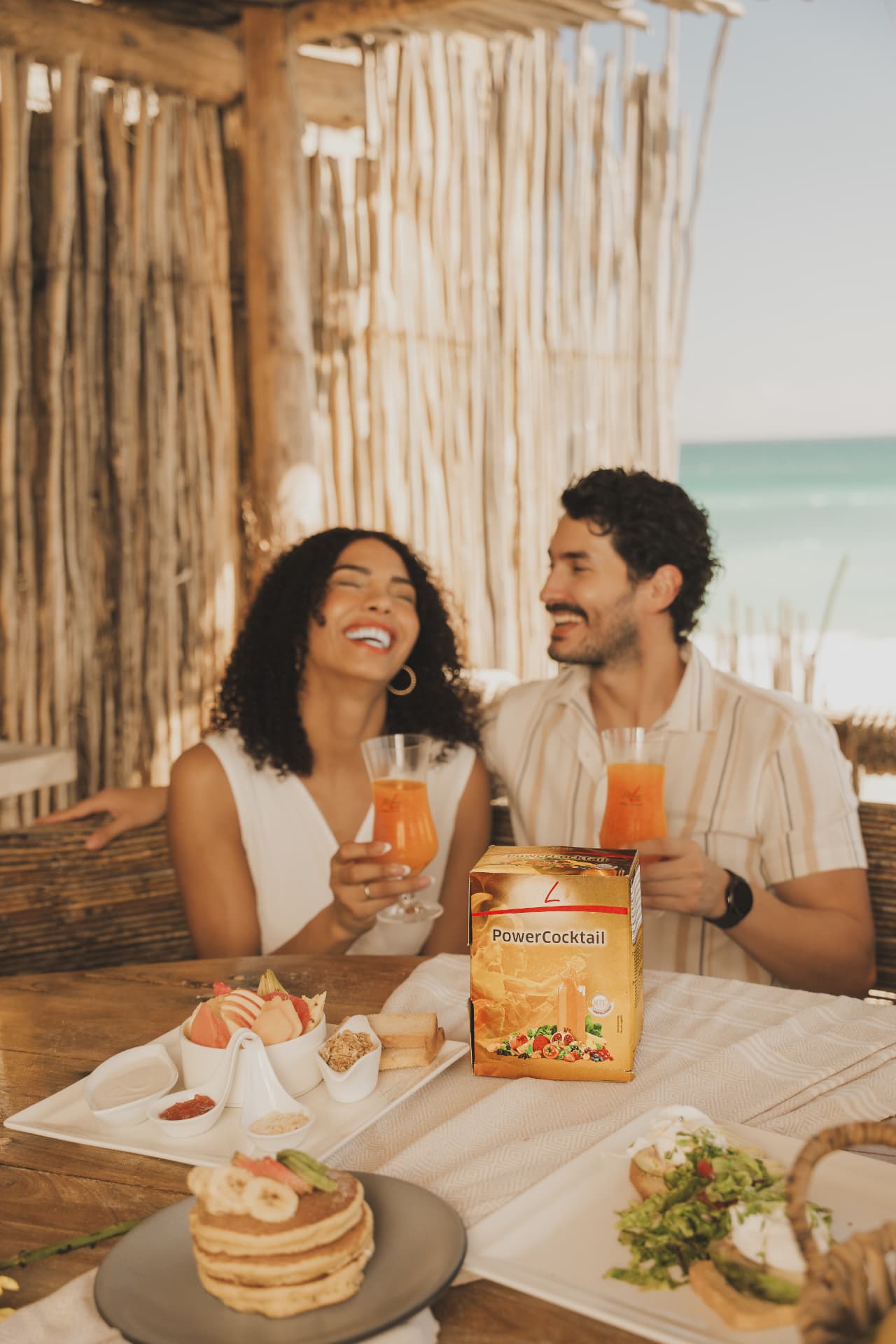 Lachend koppel aan een ontbijttafel met FitLine PowerCocktail