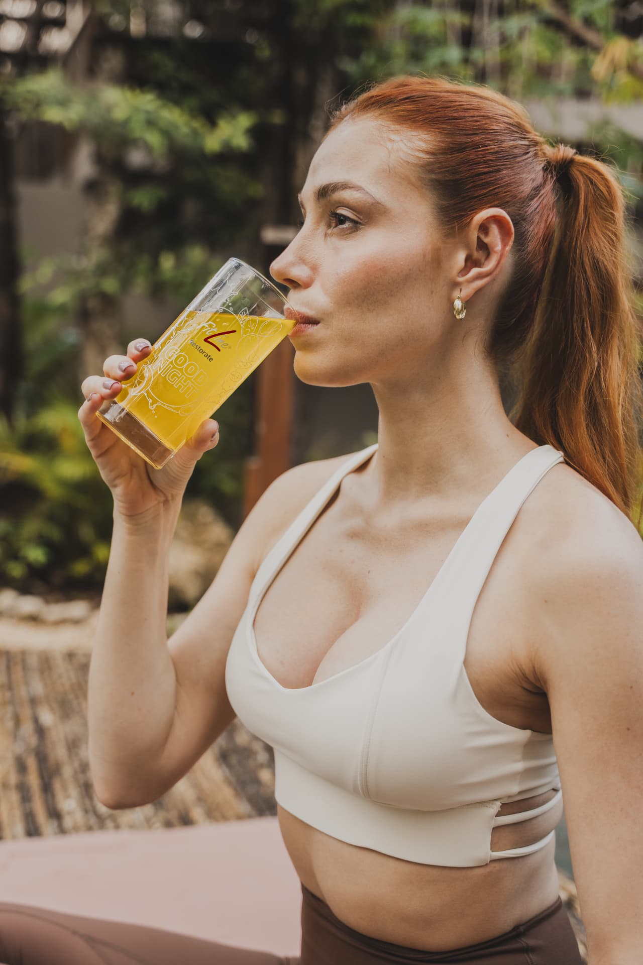 Vrouw in sportkleding met een glas FitLine Restorate Good Night als avondritueel