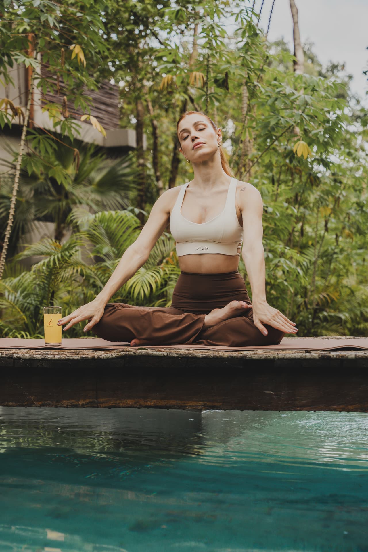 Vrouw in lotushouding op een yogamat met een glas FitLine Restorate Citrus ernaast
