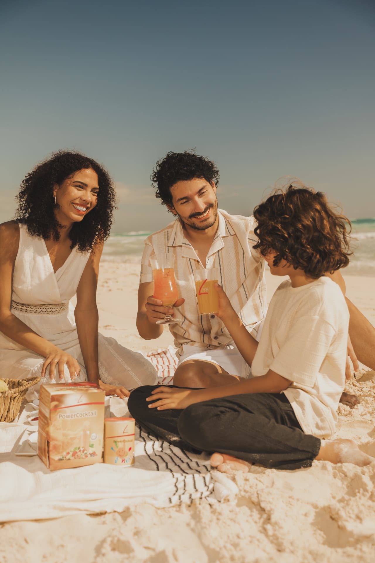 Ouders en kind proosten op het strand met FitLine PowerCocktail