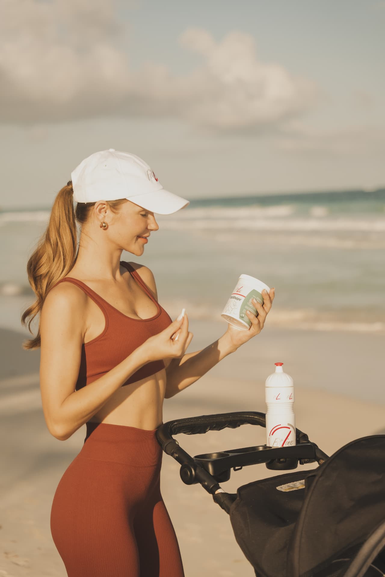 Vrouw in sportoutfit op het strand die FitLine TopShape inneemt