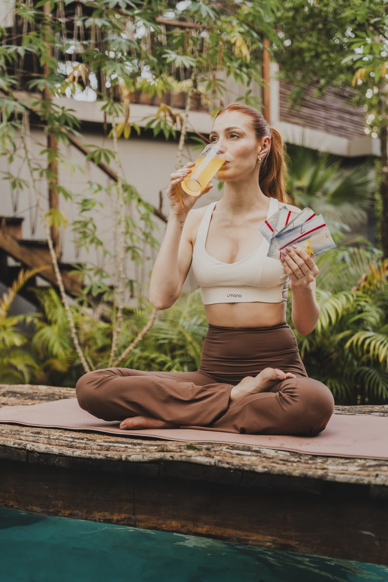 Vrouw op een yogamat die FitLine Restorate Citrus drinkt met sachets in haar hand